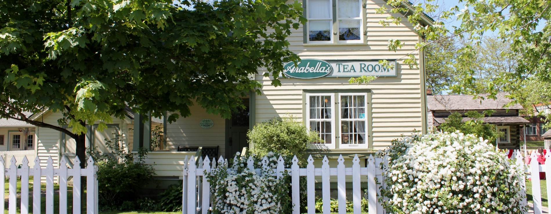 A family sitting around a table on the porch at Arabella tea room and smiling at the camera